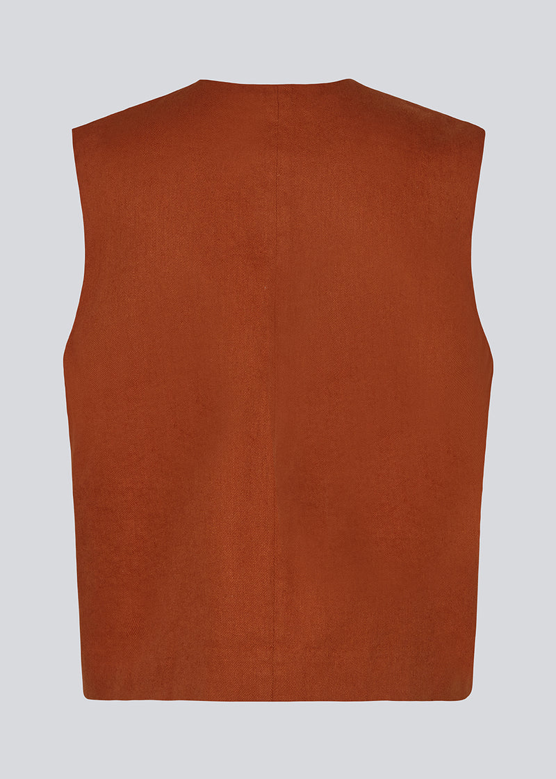 Short dark red waistcoat in a woven linen blend. ParkMD vest has a deep v-neck with buttons and a relaxed and a loose silhouette. The model is 175 cm and wears a size S/36.