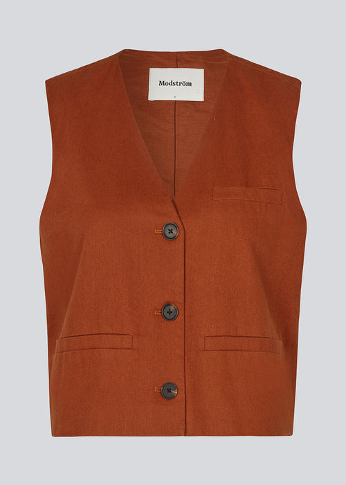 Short dark red waistcoat in a woven linen blend. ParkMD vest has a deep v-neck with buttons and a relaxed and a loose silhouette. The model is 175 cm and wears a size S/36.