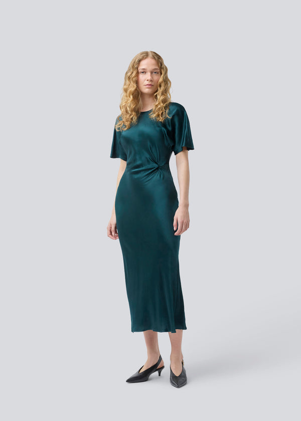 Green long satin dress with draping detail. Parveenmd dress has short sleeves and an invisible zipper in the back. The model is 175 cm and wears a size s/36.
