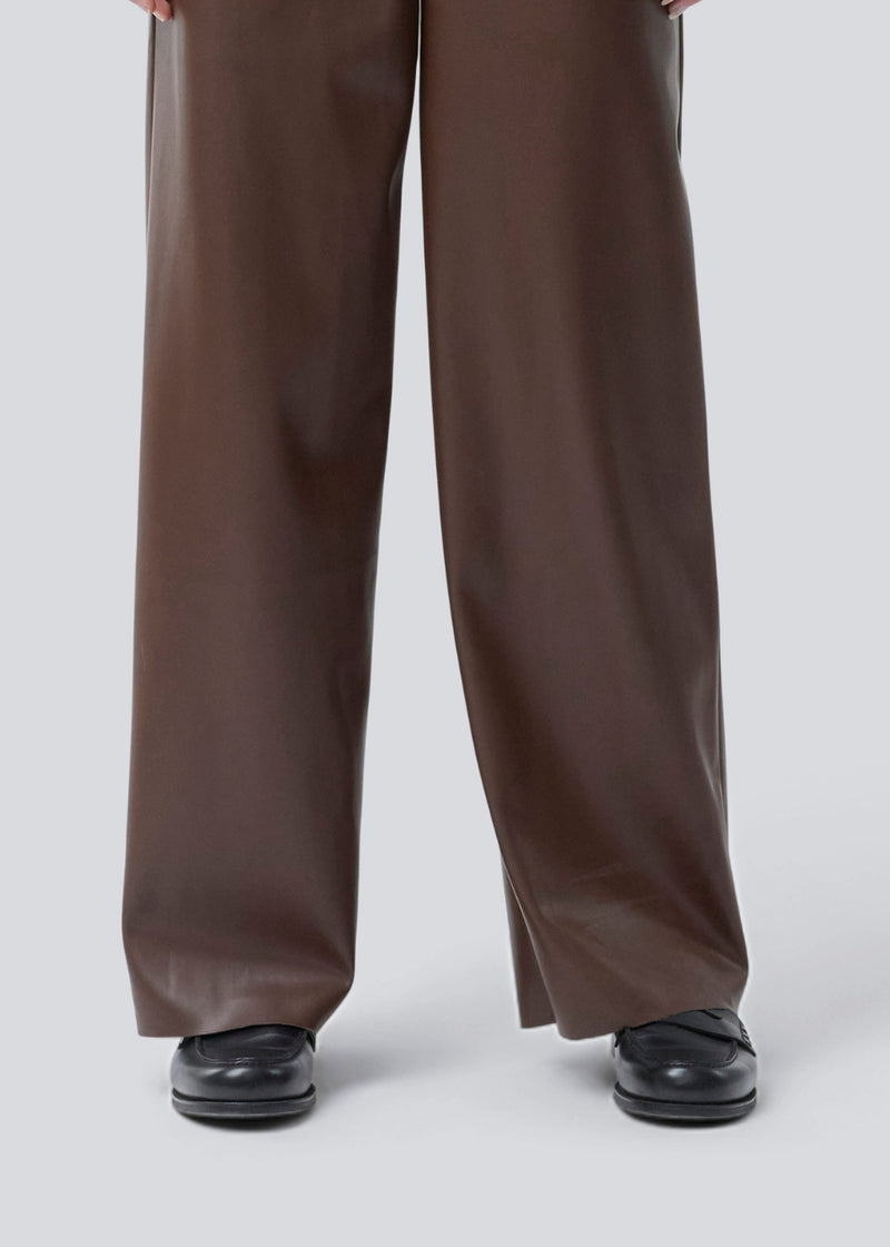 Loose trousers in 100% PU. Pellemd pants have a high waist with elastic and side pockets. The model is 175 cm and wears a size s/36.