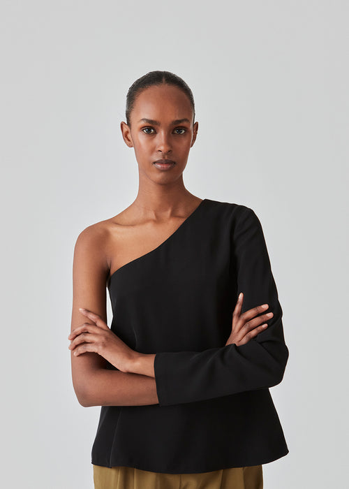 One shoulder top in black with one long sleeve in a light, woven quality. PerryMD top has a loose silhouette. The model is 175 cm and wears a size S/36. The model is 173 cm and wears a size S/36