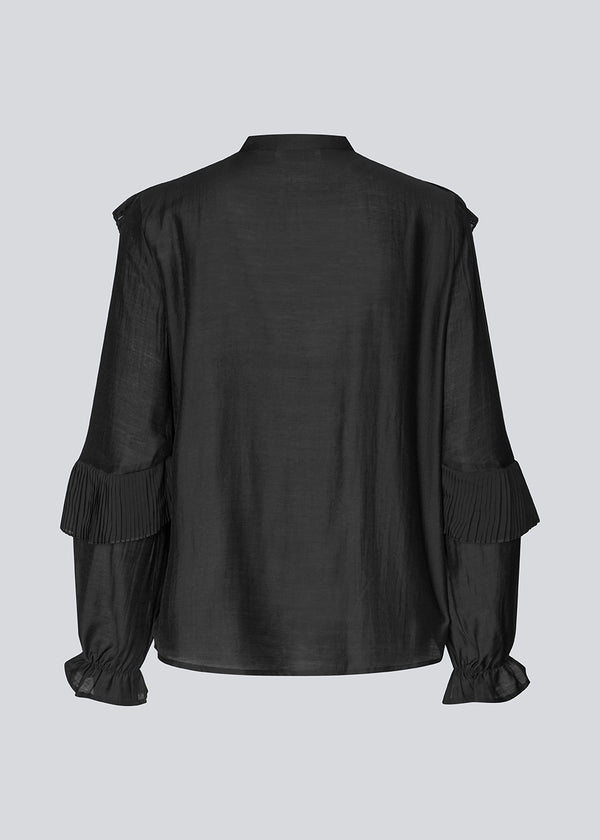 Black Shirt with ruffle details and a front opening. Phungmd shirt has a loose fit and flowy sleeves.