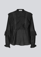 Black Shirt with ruffle details and a front opening. Phungmd shirt has a loose fit and flowy sleeves.