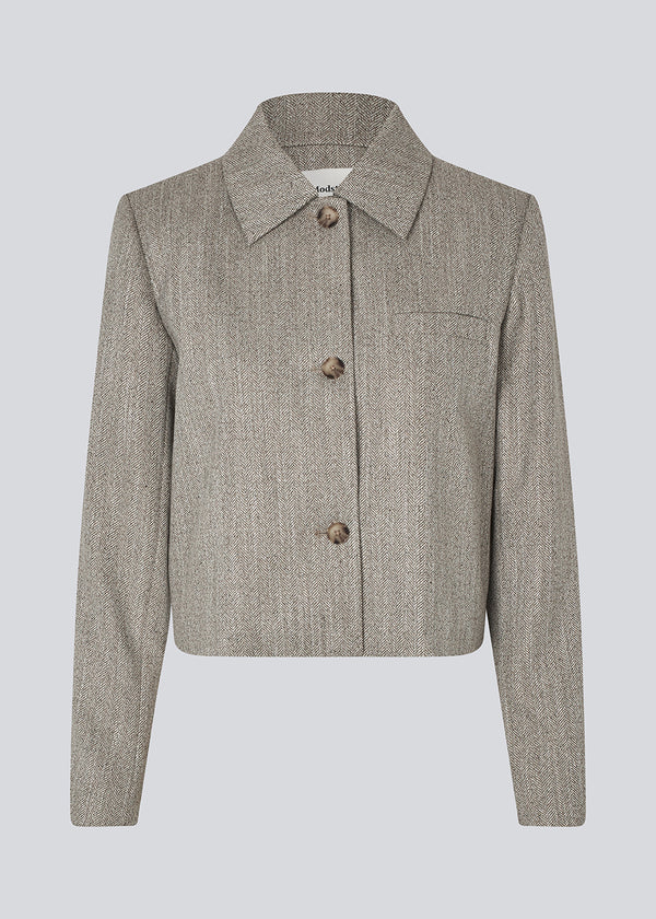Short jacket with a shirt collar and front button closure. Popemd jacket has long sleeves with slits and a chest pocket. The model is 175 cm and wears a size S/36.