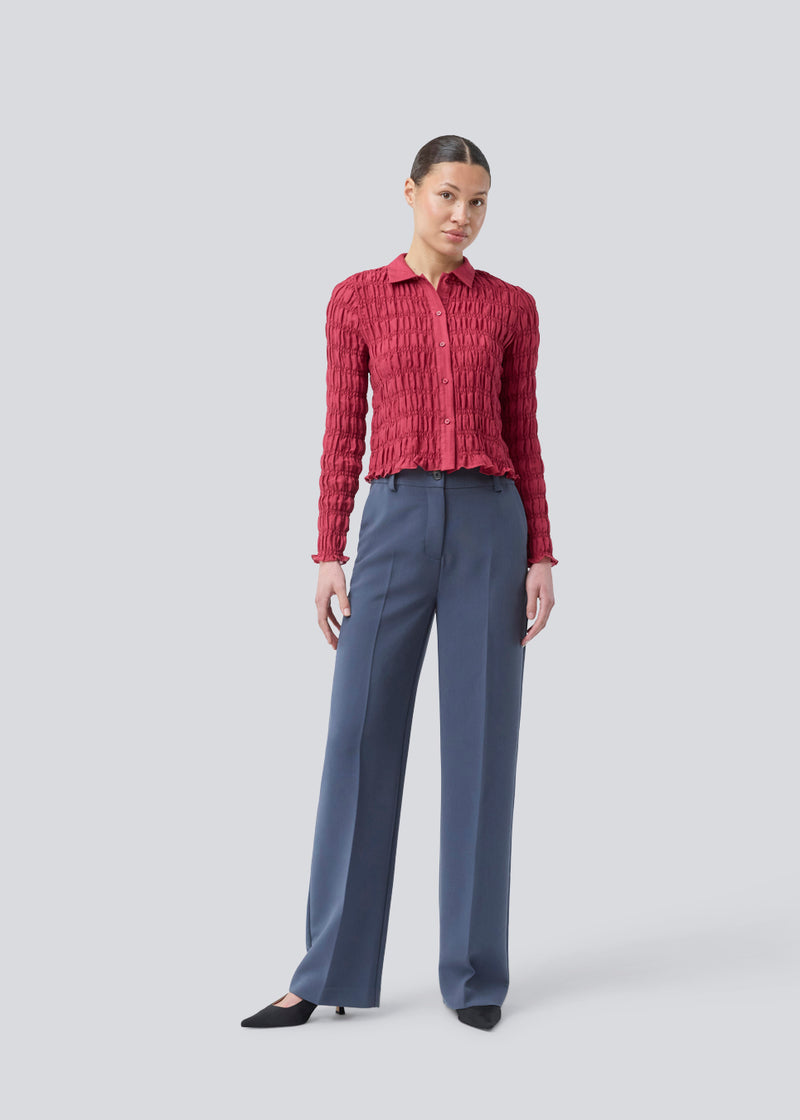 Fitted long-sleeved top in smock. Posiemd shirt has a button closure and a shirt collar. The model is 175 cm and wears a size s/36.