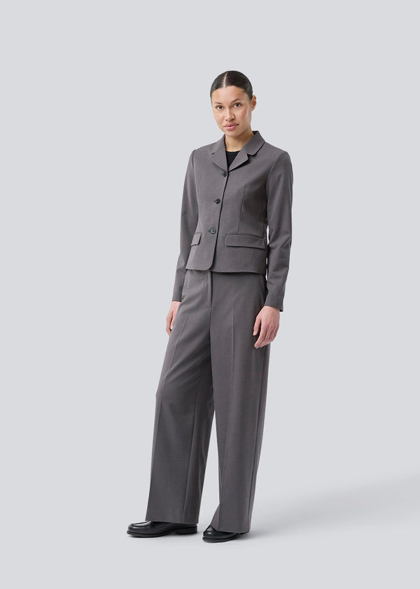 Grey short fitted blazer. Primrosemd blazer has a button closure and two front pockets. The model is 175 cm and wears a size s/36.