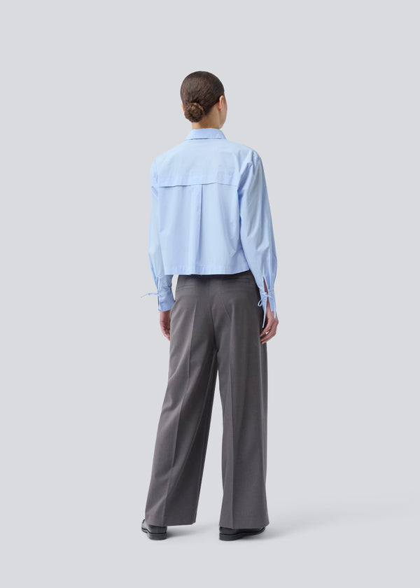 Grey long suit trousers with wide legs. Primrosemd pants have pleats and side pockets. The model is 175 cm and wears a size s/36.