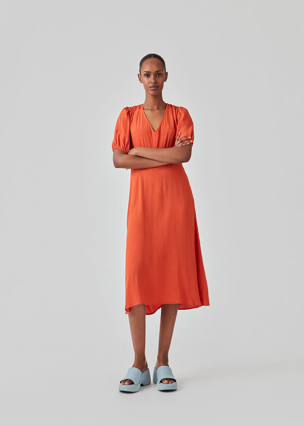 Feminine dress in red solid EcoVero viscose. RavenMD long dress is full length with flattering smock details on shoulder and waist. The model is 173 cm and wears a size S/36
