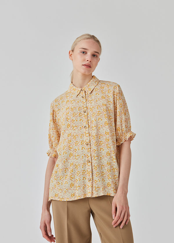 Floral printed shirt in the color Bobble Bloom Peach in a relaxed silhouette with short puffy sleeves with elastic. RavenMD print shirt has a normal collar and buttons at front. The model is 173 cm and wears a size S/36
