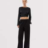 Black trousers with wide legs and pleats. The Ridermd pants feature side pockets and an elastic waistband – sleek and comfortable at the same time.