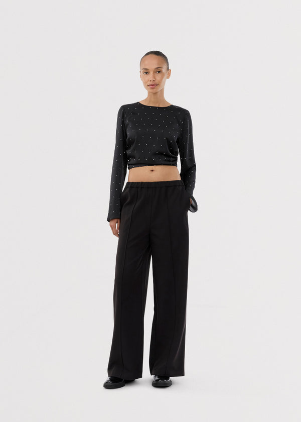 Black trousers with wide legs and pleats. The Ridermd pants feature side pockets and an elastic waistband – sleek and comfortable at the same time.