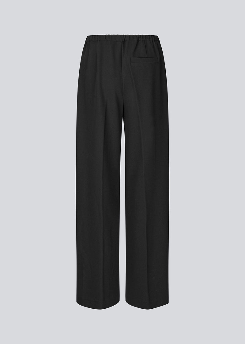 Black trousers with wide legs and pleats. The Ridermd pants feature side pockets and an elastic waistband – sleek and comfortable at the same time.