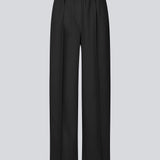 Black trousers with wide legs and pleats. The Ridermd pants feature side pockets and an elastic waistband – sleek and comfortable at the same time.