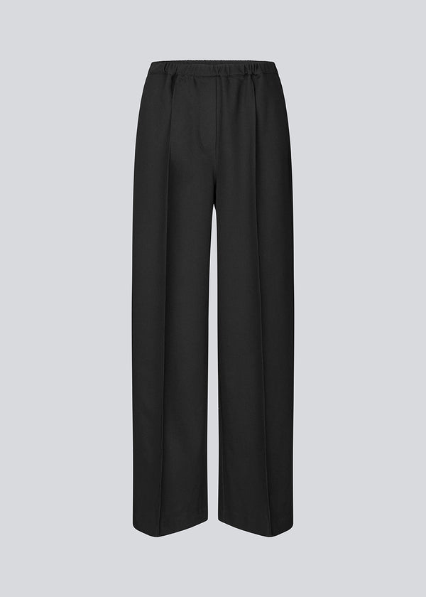 Black trousers with wide legs and pleats. The Ridermd pants feature side pockets and an elastic waistband – sleek and comfortable at the same time.