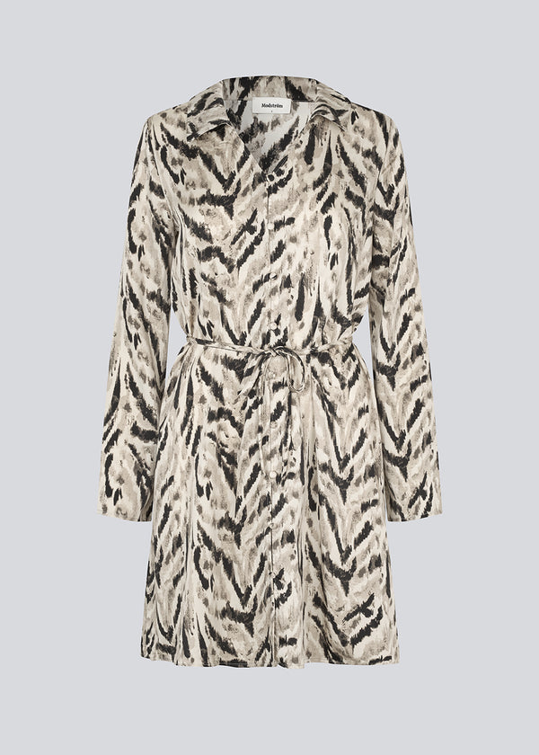 Printed shirt dress in 100% recycled polyester with collar, V-neck and button closure. The Saber-limbed Print Dress has a tie at the waist and a knee length for a flattering cut.
