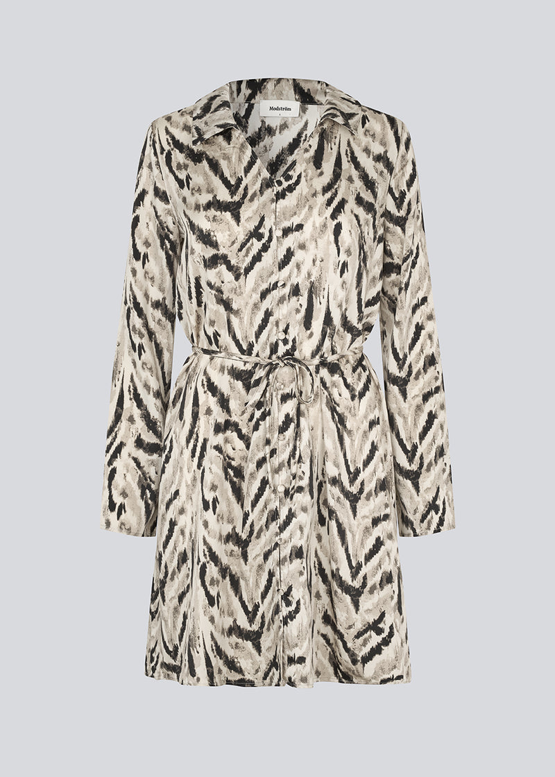 Printed shirt dress in 100% recycled polyester with collar, V-neck and button closure. The Saber-limbed Print Dress has a tie at the waist and a knee length for a flattering cut.
