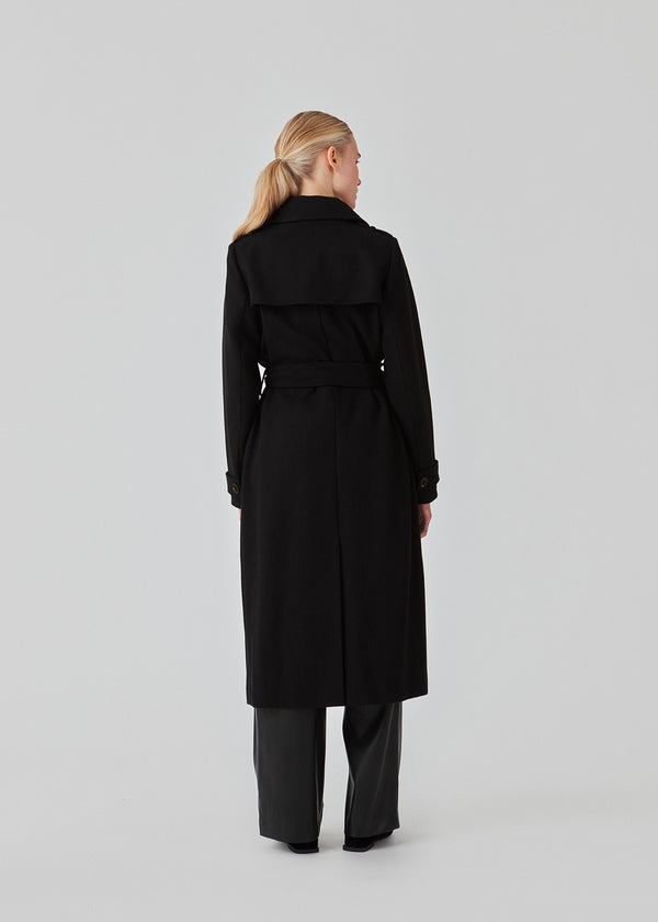 Classic, double-breasted wool coat in black with collar and notch lapels. ShayMD coat has a wide tiebelt at waist, shoulder straps, wide cuffs and open yoke. With lining and single back vent.