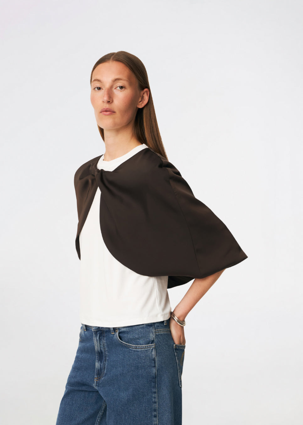Tailormd Cape is an elegant satin cape designed to add a refined and dramatic finish to any outfit. It drapes effortlessly over the shoulders and fastens at the front with a decorative knot detail, creating a soft, fluid silhouette. Layer it over a dress for special occasions or style it with a simple top for an elevated, sophisticated look. The model is 175 cm tall and is wearing a size S/36.