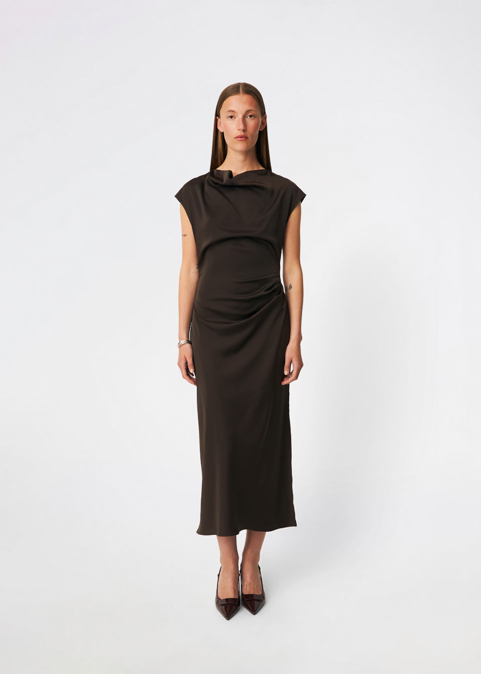 Sleeveless maxi dress with pleats in the side. TailorMD dress is made in satin and has a high neck, invisible zipper in the back and a slit in the side seam. The model is 175 cm and wears a size s/36.