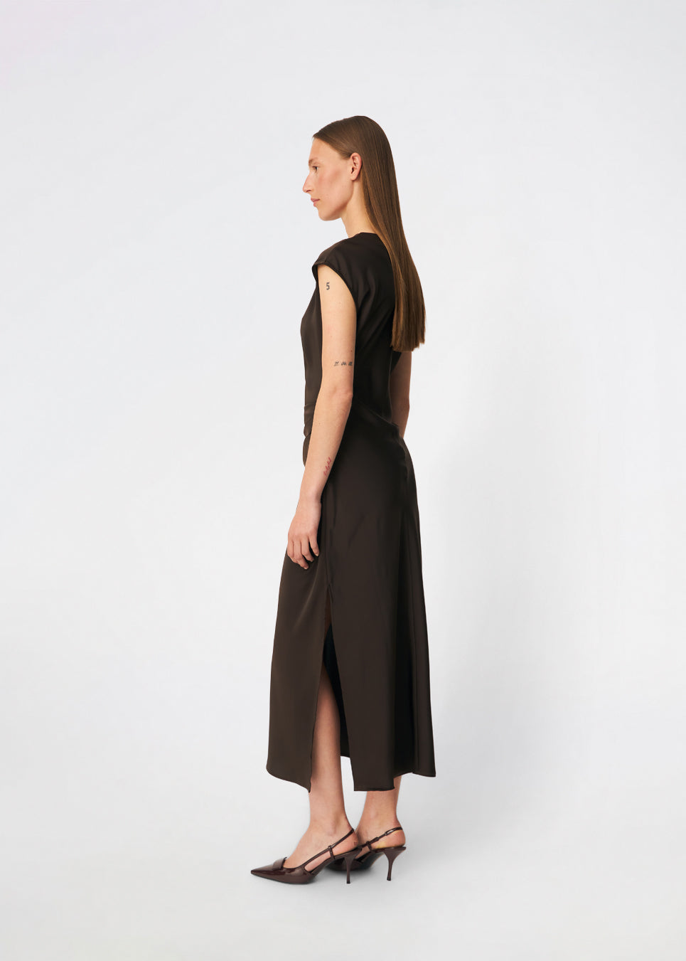 Sleeveless maxi dress with pleats in the side. TailorMD dress is made in satin and has a high neck, invisible zipper in the back and a slit in the side seam. The model is 175 cm and wears a size s/36.