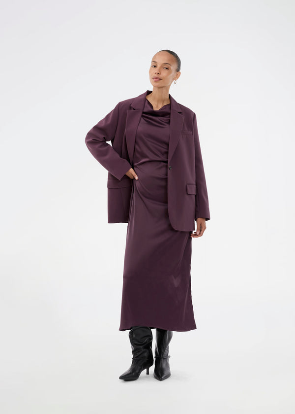 Purple sleeveless maxi dress with pleats in the side. TailorMD dress is made in satin and has a high neck, invisible zipper in the back and a slit in the side seam. The model is 175 cm and wears a size s/36.