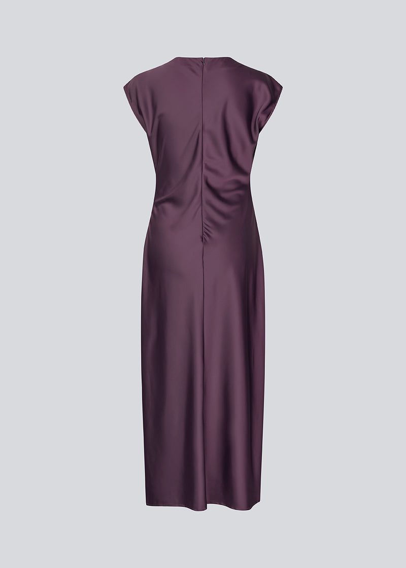 Purple sleeveless maxi dress with pleats in the side. TailorMD dress is made in satin and has a high neck, invisible zipper in the back and a slit in the side seam. The model is 175 cm and wears a size s/36.