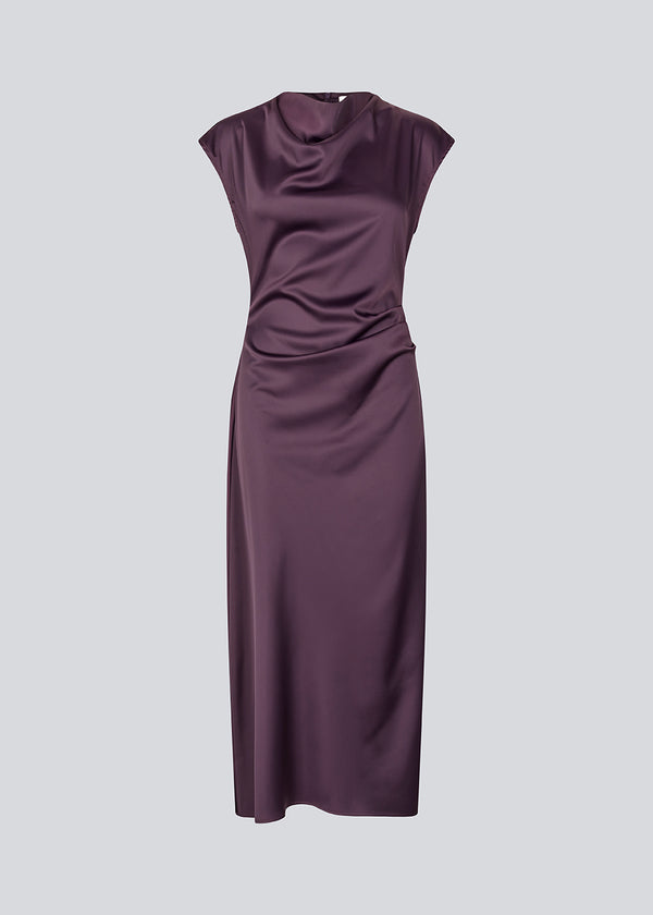 Purple sleeveless maxi dress with pleats in the side. TailorMD dress is made in satin and has a high neck, invisible zipper in the back and a slit in the side seam. The model is 175 cm and wears a size s/36.