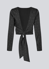 Long-sleeved satin top in black with white small dots. The TailorMD print top features a flattering open back with tie closure – combining elegance with a statement print.