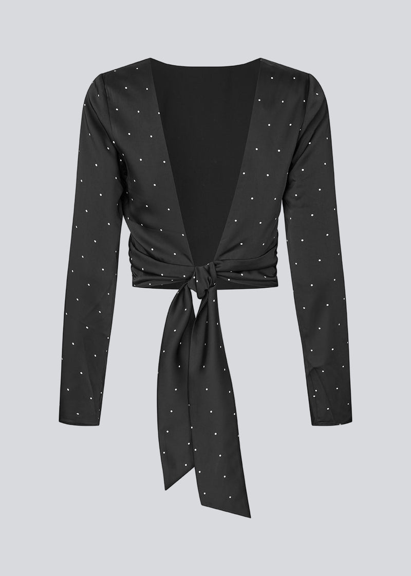 Long-sleeved satin top in black with white small dots. The TailorMD print top features a flattering open back with tie closure – combining elegance with a statement print.