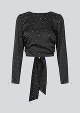 Long-sleeved satin top in black with white small dots. The TailorMD print top features a flattering open back with tie closure – combining elegance with a statement print.
