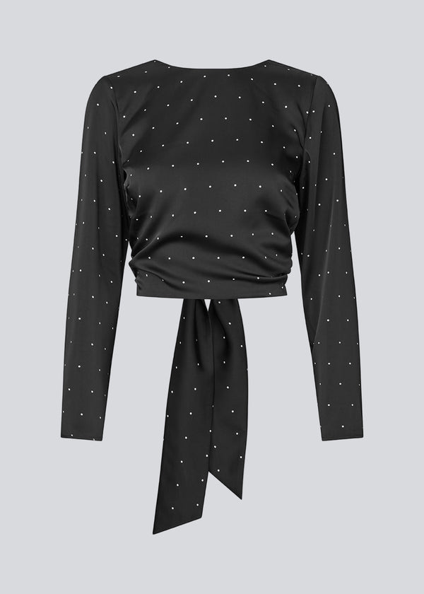 Long-sleeved satin top in black with white small dots. The TailorMD print top features a flattering open back with tie closure – combining elegance with a statement print.