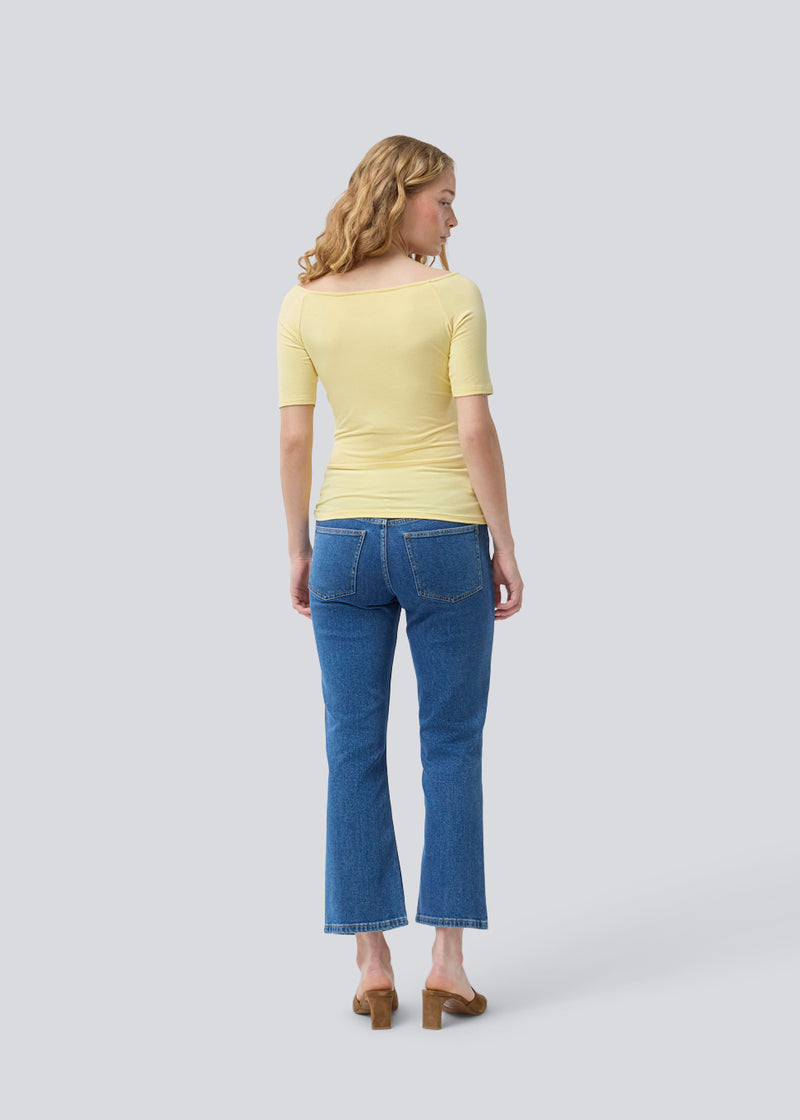 Tansy top in yellow has a simple look with a wide neckline at front and back and narrow sleeves. The top is slim fit without being tight. The model is 174 cm and wears a size S/36