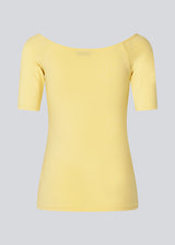 Tansy top in yellow has a simple look with a wide neckline at front and back and narrow sleeves. The top is slim fit without being tight. The model is 174 cm and wears a size S/36