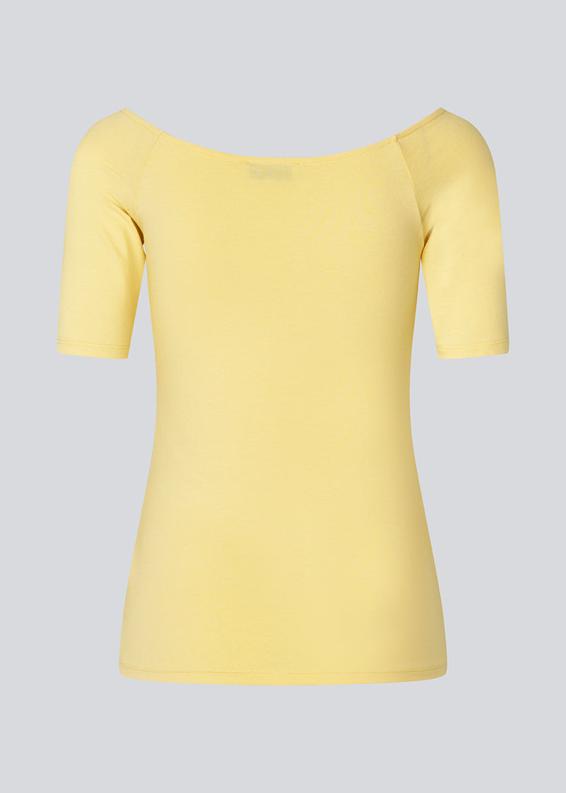 Tansy top in yellow has a simple look with a wide neckline at front and back and narrow sleeves. The top is slim fit without being tight. The model is 174 cm and wears a size S/36
