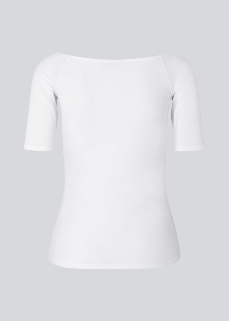 Tansy top in white has a simple look with a wide neckline at front and back and narrow sleeves. The top is slim fit without being tight.
