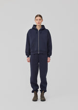 <p>Sweatshirt in navy blue with a zipper and logo in a cotton mixture. TiaMD Zip has pockets, ribbing at the sleeves and bottom, and a hood with strings.</p> <p><a href="https://modstrom.com/products/tiamd-pants-navy-sky" title="tiamd-pants-navy-sky">Style with matching pants.</a></p>