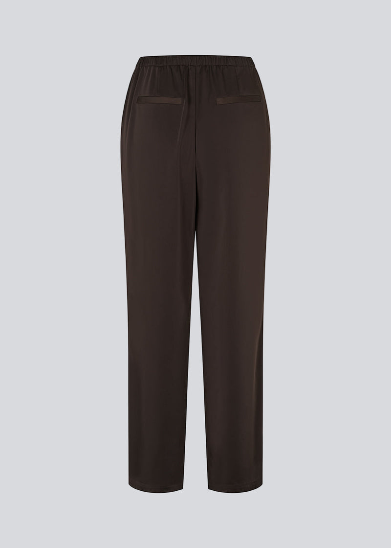 Brown loose satin pants. Timmiemd pants has wide legs, sidepockets, and a tiefastening. A relaxed fit with an elegant look.