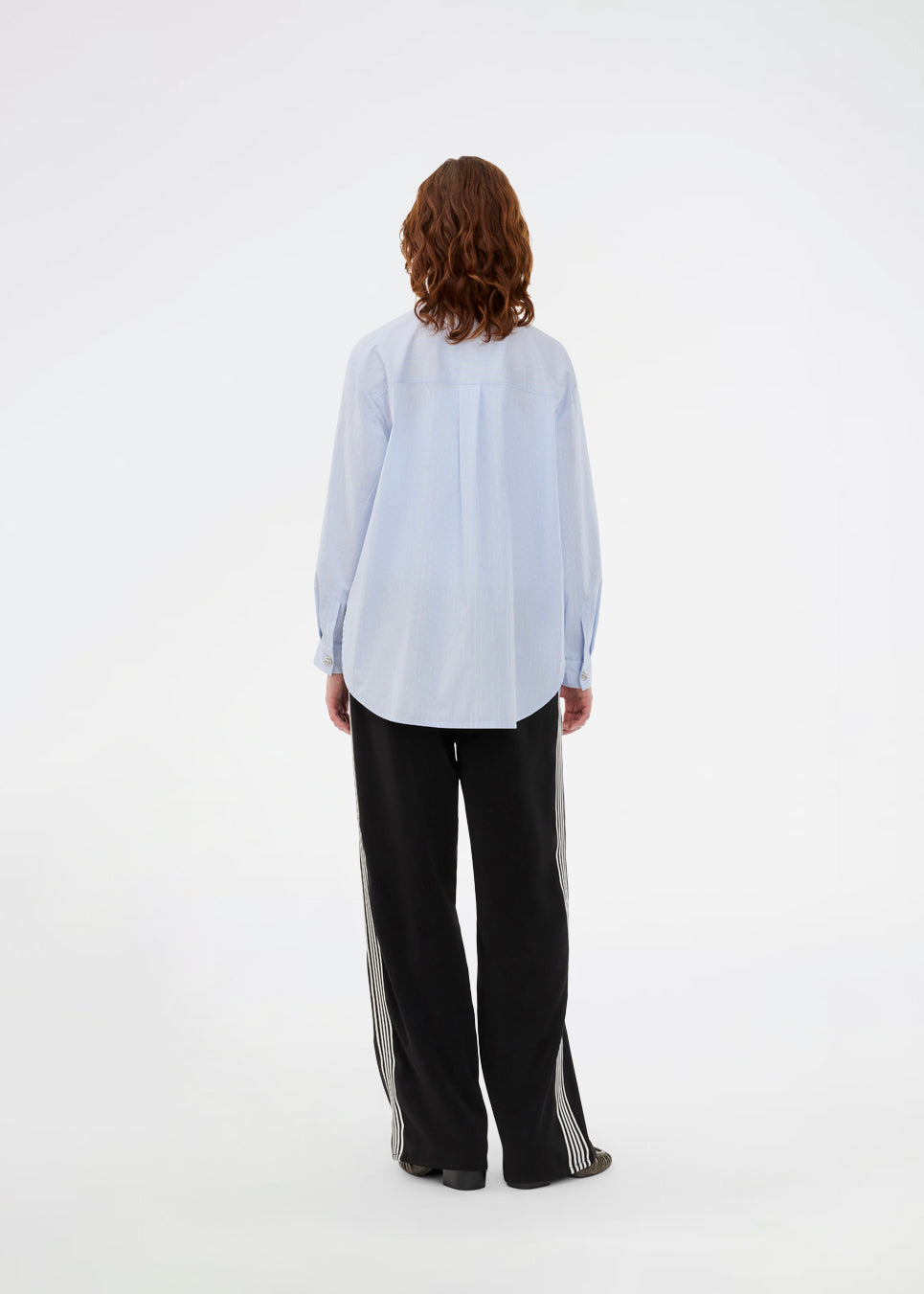 Loose black trousers with wide legs and a relaxed fit. Featuring an elastic waistband with drawstring for a comfortable, adjustable waist. White side stripes add a sporty and modern touch to the otherwise classic design. Perfect for casual everyday wear or more elevated styling – easy to pair with everything from t-shirts to dressy tops.
