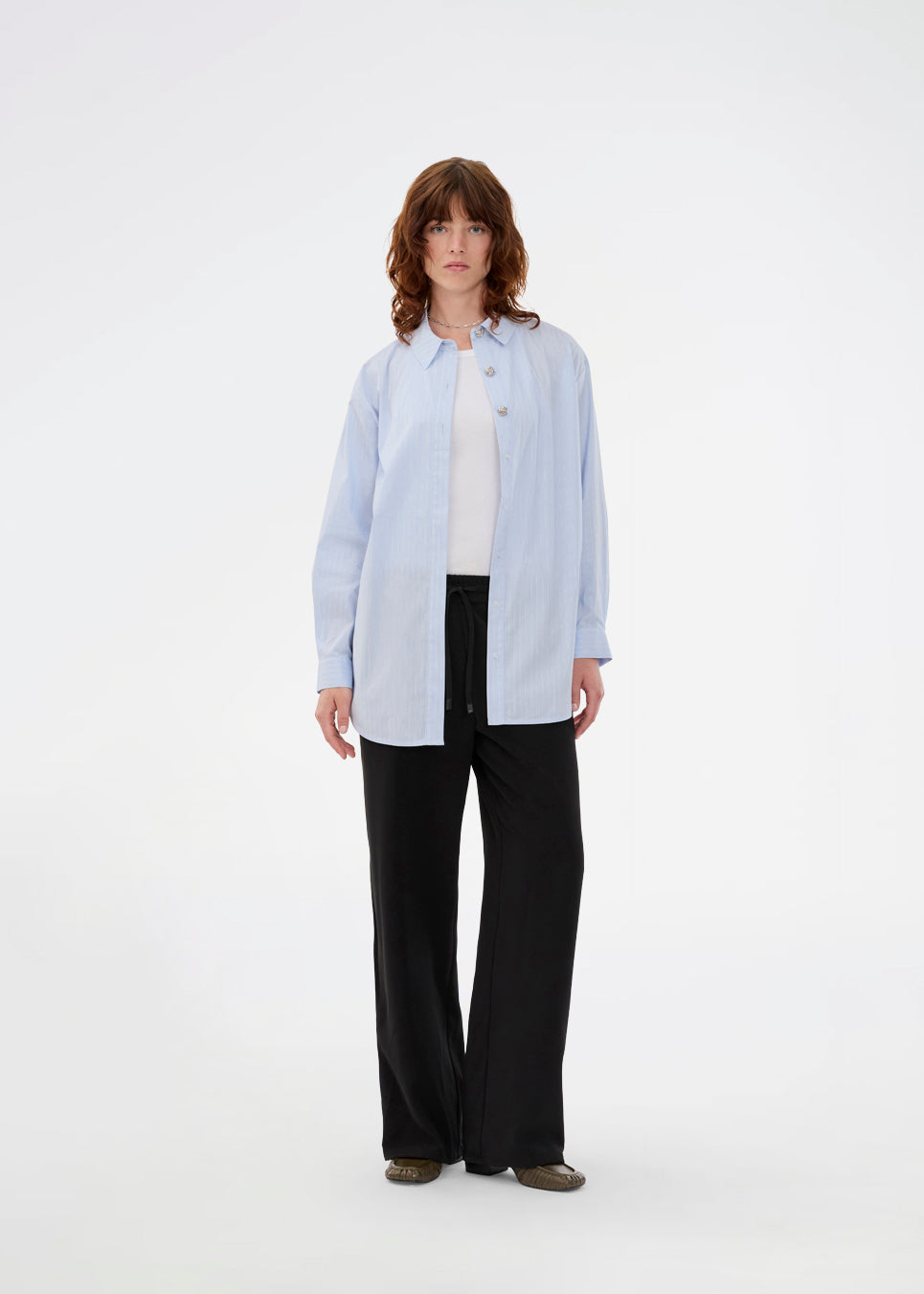 Loose black trousers with wide legs and a relaxed fit. Featuring an elastic waistband with drawstring for a comfortable, adjustable waist. White side stripes add a sporty and modern touch to the otherwise classic design. Perfect for casual everyday wear or more elevated styling – easy to pair with everything from t-shirts to dressy tops.
