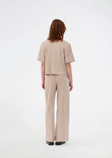 Suit pants in beige with pleats and wide leg. Tuesdaymd pants have a medium-highwaist, zipper, side pockets and paspoil pockets in the back. The model is 175 cm and wears a size s/36.