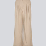 Suit pants in beige with pleats and wide leg. Tuesdaymd pants have a medium-highwaist, zipper, side pockets and paspoil pockets in the back. The model is 175 cm and wears a size s/36.
