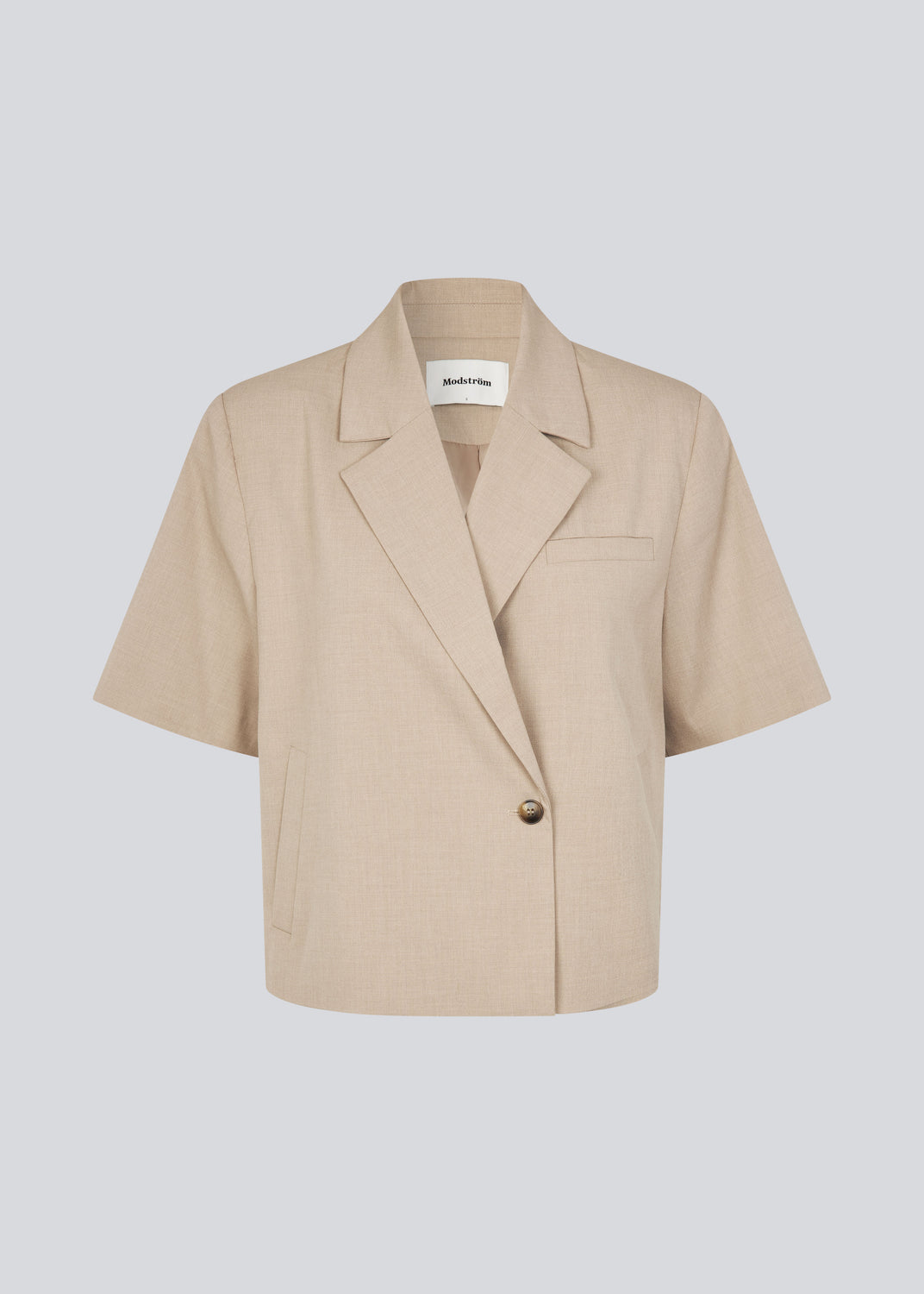 Short-sleeved blazer with a single-button closure. The TuesdayMD SS Blazer features a crossover button closure, collar, side pockets, and a faux chest pocket – a modern twist on a timeless classic. Can be worn closed as an elegant top or open over a light blouse for a more relaxed look.
