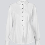 A modern interpretation of the classic shirt in white. The UllisMD Shirt is made from 97% organic cotton and designed with a pointed collar, half button closure, and a feminine, fitted silhouette that creates an elegant and sophisticated look. The model is 175 cm and wears a size S/36.

Material:
97% Organic Cotton
3% Elastane