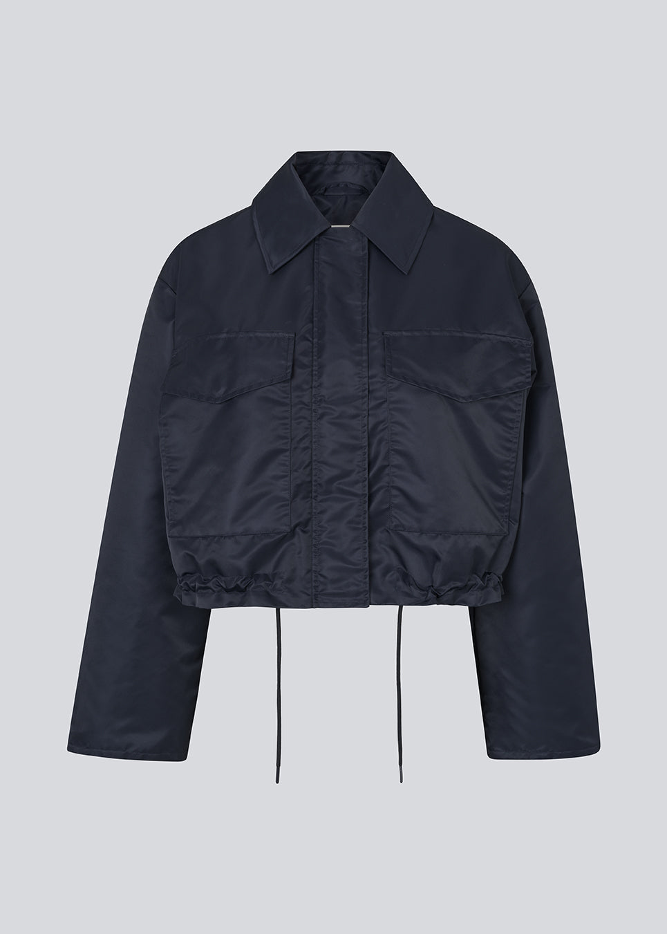 Short jacket in navy with modern and practical details. The Ulrikkemd jacket features a classic collar, large front flap pockets, an adjustable drawstring at the waist, and is crafted from glossy nylon that gives it a sleek and sporty look. The model is 175 cm and wears a size S/36.

Material:
100% Nylon

Lining:
100% Polyester

Filling:
100% Polyester