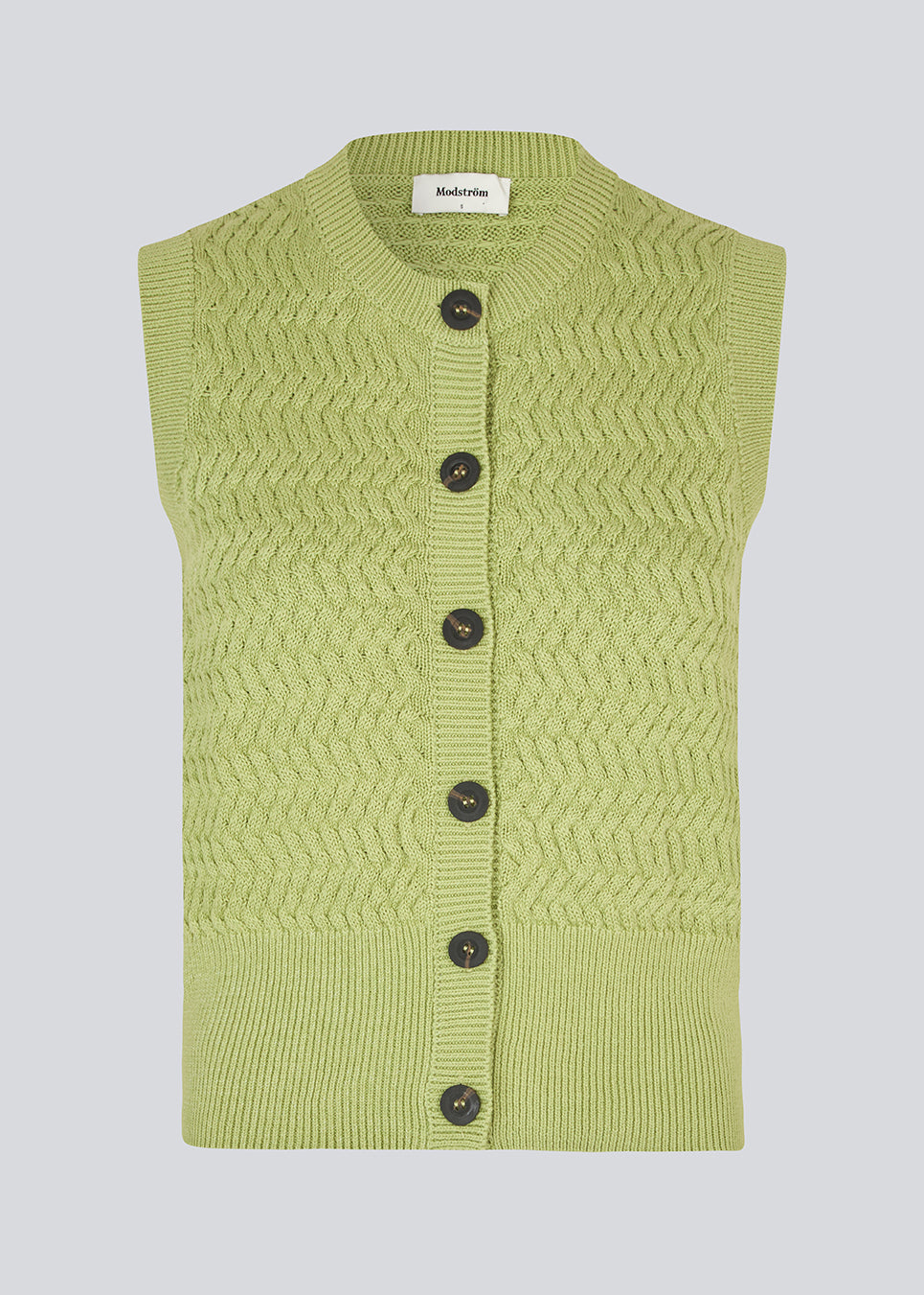 Knitted sleeveless top in green made from 100% organic cotton. The UlvaMD Top is crafted in a beautiful herringbone knit with a wide ribbed hem and trim. The contrast buttons and round neckline give the top a refined and feminine look. The model is 175 cm and wears a size S/36.


Material:
100% Organic Cotton