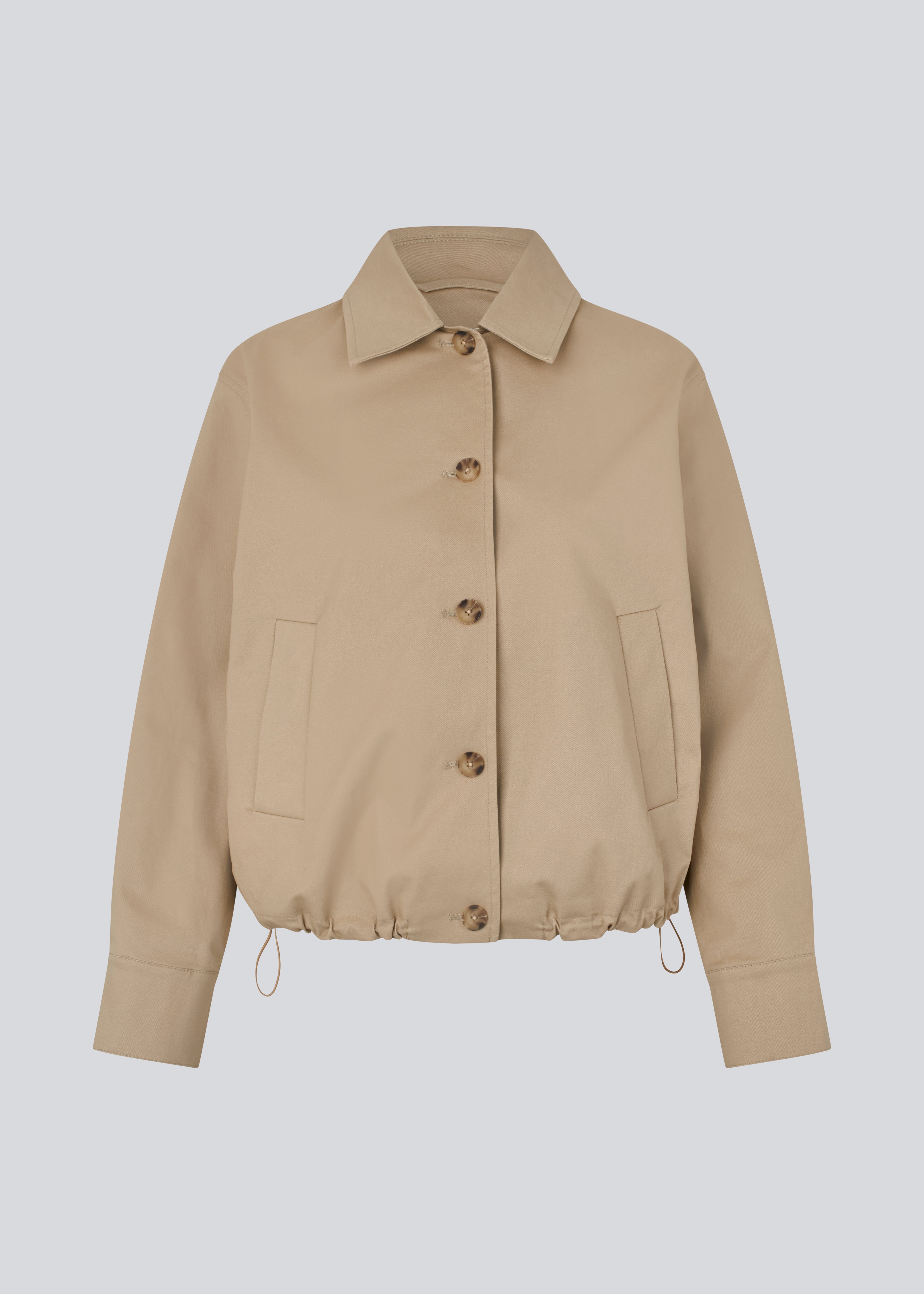 Short jacket i beige with a trench coat look. The Umamd jacket features a shirt collar, side pockets, button closure, and an adjustable elastic hem. The model is 175 cm and wears a size S/36.

Material:
97% Cotton
3% Elastane

Lining:
100% Polyester