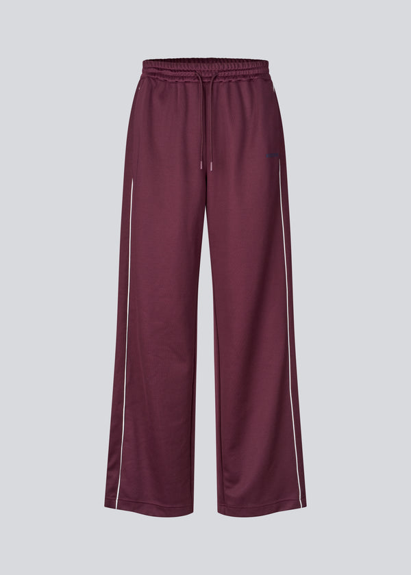 Dark red tracksuitpants with wide legs in 100% recycled polyester. Utopiamd pants has sidepockets, logo and an elastic waistband with tiebands.