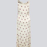 Long white satin dress with polka dots. The Vanjamd Print Dress features delicate spaghetti straps, a cowl neckline, and a loose, elegant drape that creates a feminine and modern look.