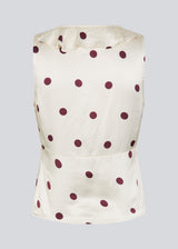 Polka-dotted sleeveless top with a ruffle trim. The Vanjamd Print Top is made from lustrous satin and features feminine details such as a V-neckline, ruching, and a tie detail under the bust for an elegant look.