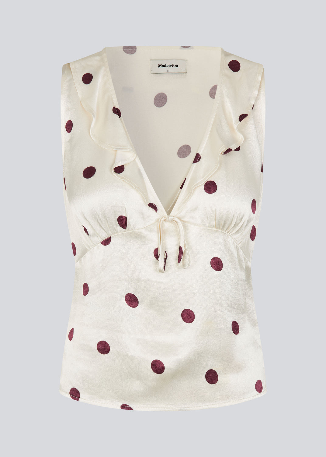 Polka-dotted sleeveless top with a ruffle trim. The Vanjamd Print Top is made from lustrous satin and features feminine details such as a V-neckline, ruching, and a tie detail under the bust for an elegant look.